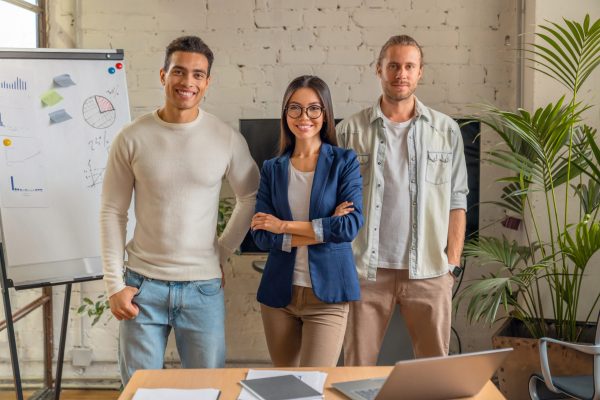 Portrait of successful business team standing together looking at camera and smiling. Positive business people in board room. Professional colleagues doing their job